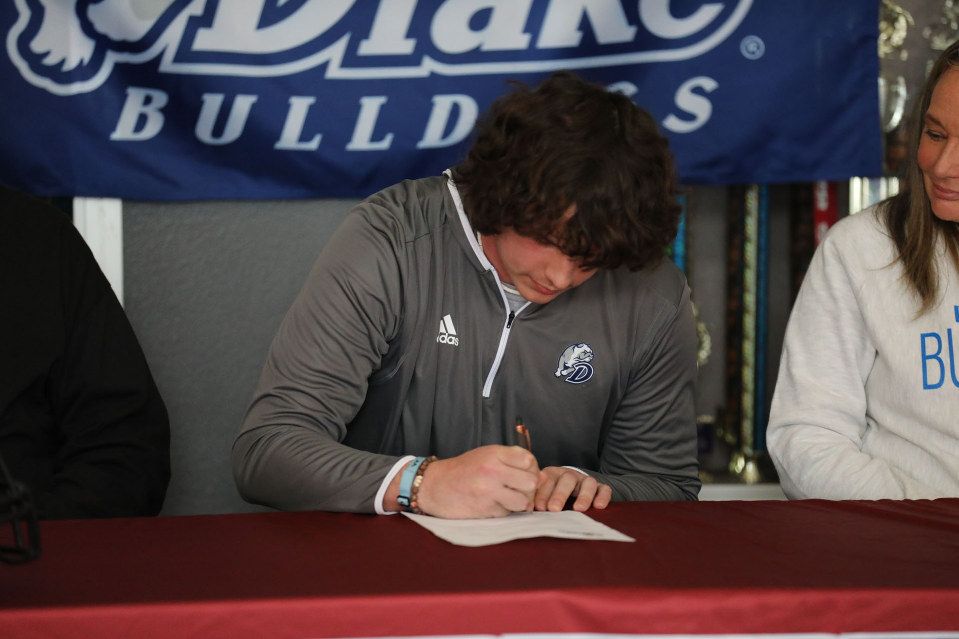 Jacob putting pen to paper to sign with Drake Football